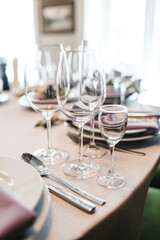 Front view of empty glassware on beige table, serving in minimalism style, silver cutlery, vine glasses. Elegant kitchen elements, preparing for  eating. Concept of stylish dish design objects