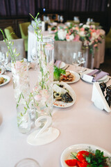 Close up of restaurant table serving decorated with transparent vases and flowers full of tasty dishes, table number two. Prom interior design and catering, preparing. Concept of wedding celebration.