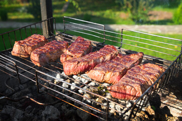 Grilled meat on a wire rack. Steaks barbecue on a brazier. Outdoor cooking.
