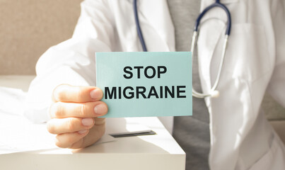 Doctor holding a card with Stop Migraine, medical concept