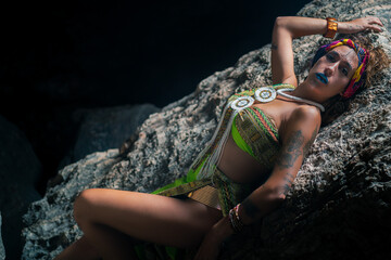 Beautiful woman dressed as Egyptian princess lying on a rock, with a black background