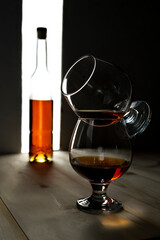 Bottle and glass of cognac over dark and white background