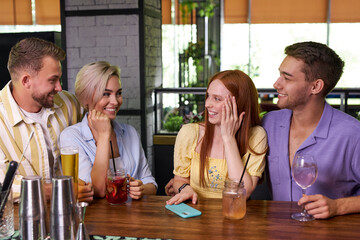 two beautiful couples have met in bar, sit talking, sharing news