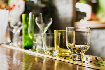 Different kinds of glasses on a bar counter, rocks, old fashioned, highball, nick and nora, coupe