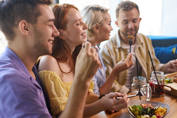 beautiful caucasian men and women hold friendly meeting in cafe, they have a great time after work, have talk. leisure, drinks, people and communication concept