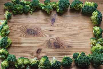 Broccoli on a light wooden background top view frame, vegetarian frame for inscription. Green vegetable background.