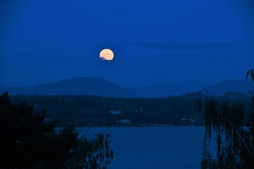 Full moon rising over mountains and lake