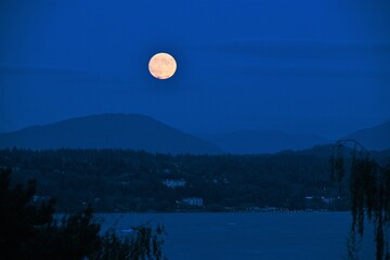 Obraz premium Full moon rising over mountains and lake