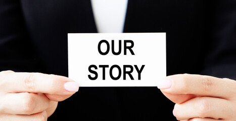 The girl businessman holds a business card with the inscription OUR STORY.