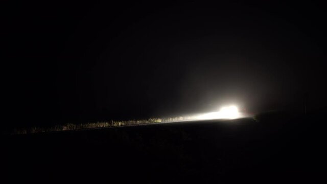 Car headlights through fog on dark country road