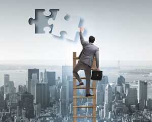 Fototapeta premium Businessman putting together jigsaw puzzle pieces