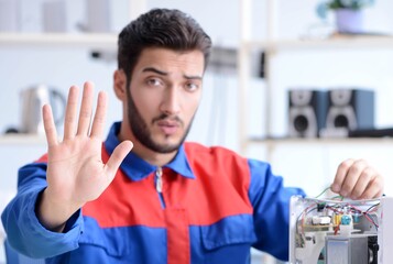 Young repairman fixing and repairing microwave oven