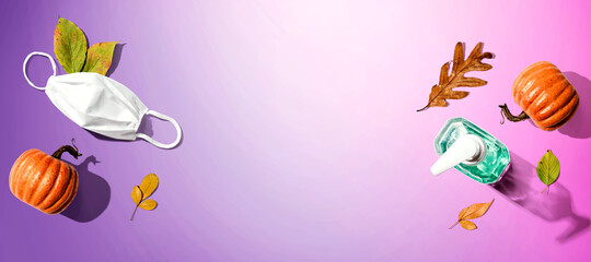 A mask and a sanitizer bottle with autumn pumpkins and leaves - healthcare and hygiene concept