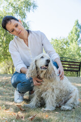 Happy woman walking her old spaniel dog in a park. Walking with pet in park at summer day. Day in the Life Series of Family elderly pet