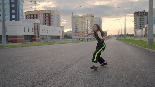 young beautiful woman dancing on a wide city street. Summer evening. Sunny sunset. Hip hop. Contemporary choreography. Slow motion. Gimbal shot