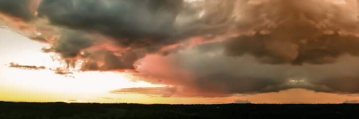 Burning sky in pink, grey, yellow and orange colors. Yellow hour during sunset up in the North of Scandinavia. Panoramic photo taken from the air by a drone.