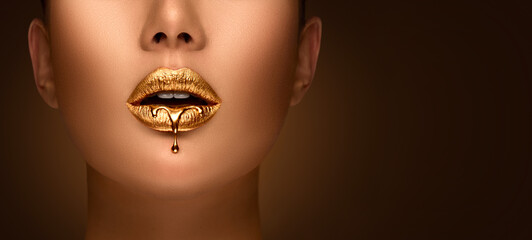 Golden lipstick closeup. Liquid metal dripping from gold lips. Beautiful makeup. Sexy lips, bright liquid paint on beautiful model girl's mouth, close-up. Lipstick.