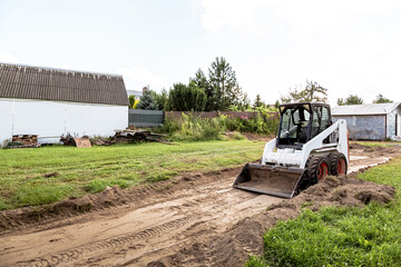 A skid steer loader clears the site for construction. Land work by the territory improvement....