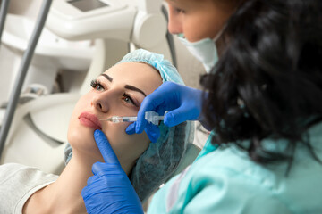 Fototapeta premium cosmetologist making injection in face, lips.