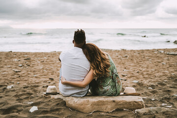 a pregnant interracial couple hugging on the beach