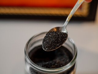 Homemade face mask and scrub with activated powder in glass jar on grey back, iron spoon with charcoal