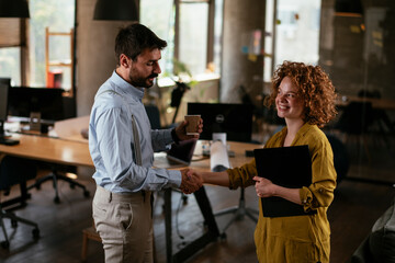 Businesswoman and businessman discussing work in office. Two friends handshake in the office.