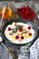 Selective focus. Breakfast bowl with raspberries, honey and seeds.