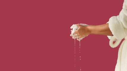 Beautiful female hands holding a bar of soap, on an isolated background. The girl is dressed in a Terry dressing gown