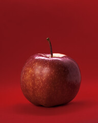 Juicy red Apple on a red background. Dark light. The concept of color, passion, healthy food. Close up photo