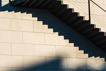 Minimalist wall with shadows from the upper steps of a modern stone staircase.