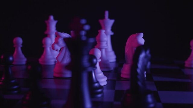 Chess pieces on a chessboard in a colorful fashion style. Studio neon light footage. Pink and purple colors. Slow tracking shot. Fashion, business concept. Depth of field, soft focus . Red camera
