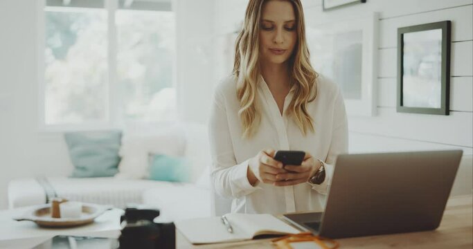 Professional young woman checks phone while working from home, keeping in touch, remote work concept
