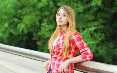 Close up portrait of blonde teenager girl in summer park looking at camera