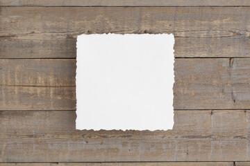 Square 8x10 deckle edge, cold pressed watercolour paper mockup. Flat lay on an old wooden, brown desk.
