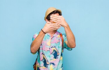 young bearded tourist man covering face with both hands saying no to the camera! refusing pictures...