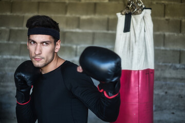 A handsome man in a black shirt punching a boxing bag