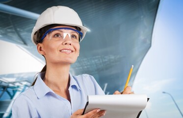 Portrait of female engineer in hard helmet making notes