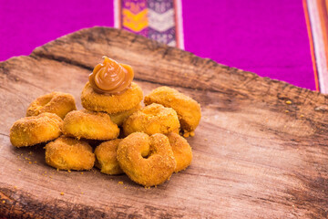 Deliciosas rosquitas y rosquillas con dulce manjar blanco  en mesa de madera rústica de los andes del Perú