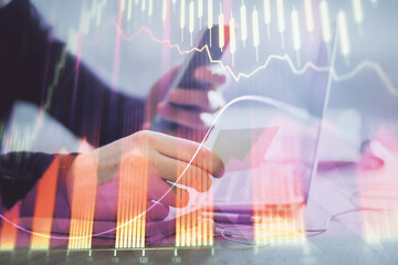 Double exposure of man's hands holding and using a phone and financial graph drawing. Analysis concept.