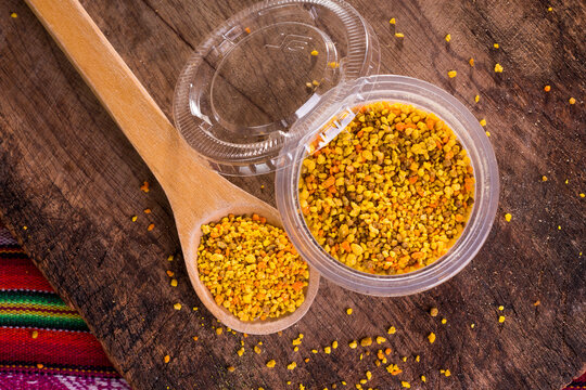Polen de abeja natural artesanal org&aacute;nico con cucharon de madera r&uacute;stica en pote de pl&aacute;stico descartable, desde los andes del Per&uacute;.