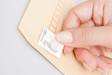 封筒に切手を貼る女性の手元
