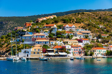 Fototapeta na wymiar Turquoise colored bay in Mediterranean sea with beautiful colorful houses in Assos village in Kefalonia, Greece. Town of Assos with colorful houses on the mediterranean sea, Greece.