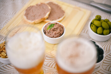Obraz na płótnie Canvas Tostadas con leberwurst acompañado por aceitunas, maní y cerveza