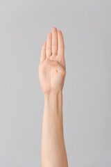 Hand showing letter B on grey background. Sign language alphabet