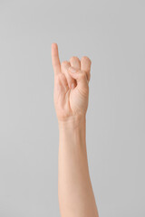 Hand showing letter I on grey background. Sign language alphabet