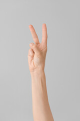 Hand showing letter K on grey background. Sign language alphabet