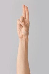 Hand showing letter U on grey background. Sign language alphabet