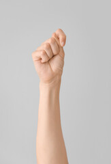Hand showing letter T on grey background. Sign language alphabet