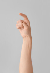 Hand showing letter X on grey background. Sign language alphabet