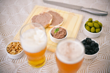 Tostadas con leberwurst acompañado por aceitunas, maní y cerveza